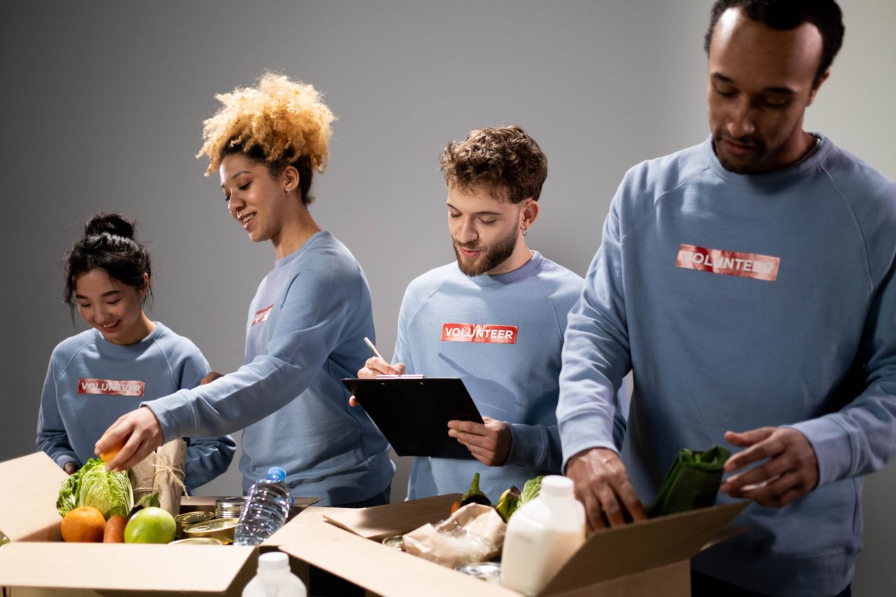 Quatre bénévoles aux profils variés préparent des dons alimentaires avec esprit d’équipe et engagement.